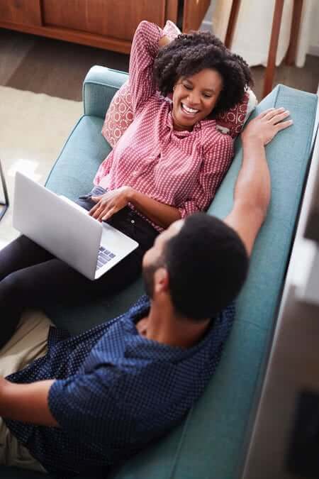 happy couple on couch with laptop image